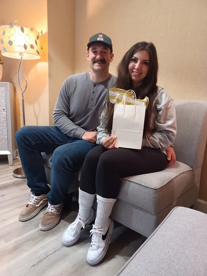 Smiling couple sitting together on a couch during a personalized surrogacy consultation.