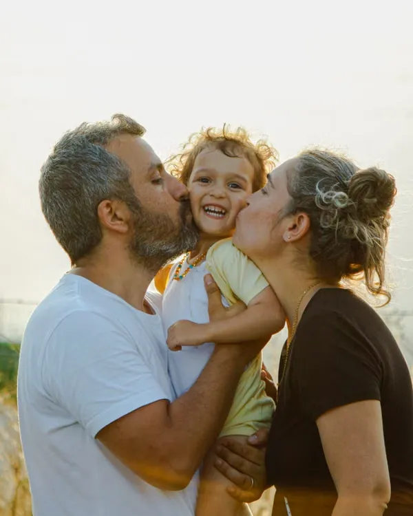 Parents kissing their child outdoors in San Diego.