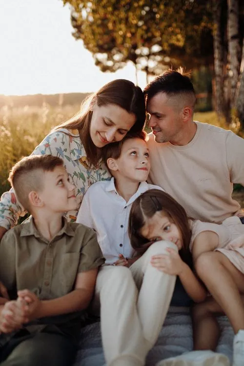 Happy family of five smiling together outdoors.