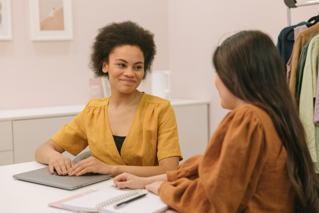 A smiling gestational surrogate speaking with a family coordinator during a consultation.